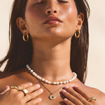 sleek and simple every day medium sized waterproof gold hoop paired with freshwater pearl necklace